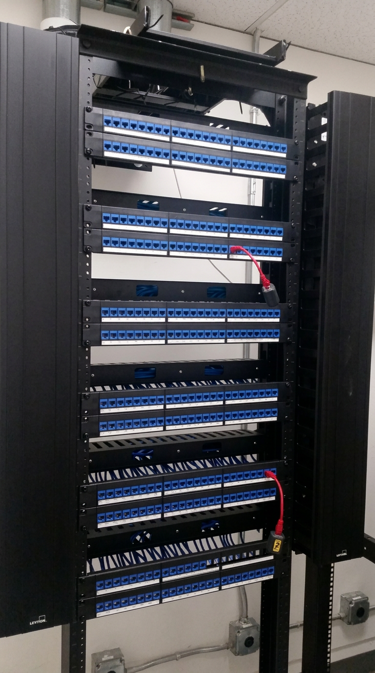 Floor-standing enterprise rack with Leviton cable managers and stacked blue Cat6 patch panels.