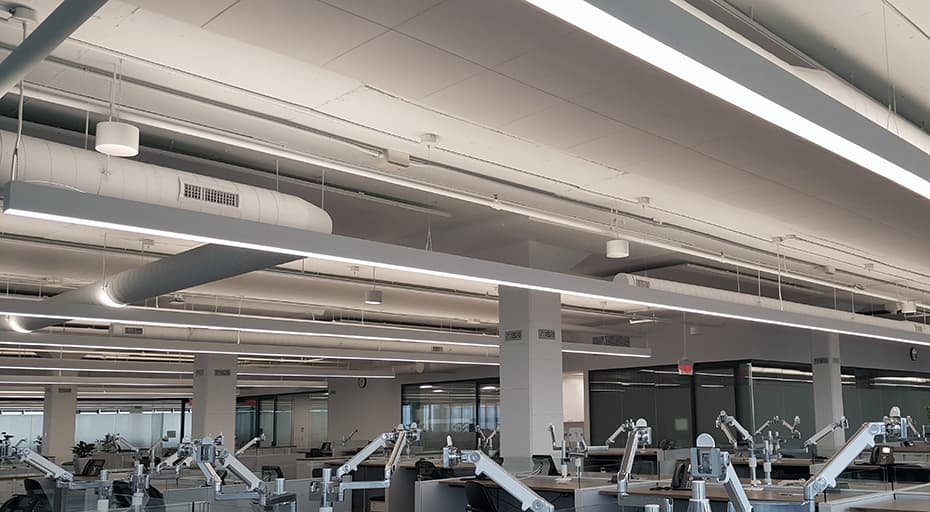 Open office ceiling with linear lighting and sound masking emitters installed above the workstations