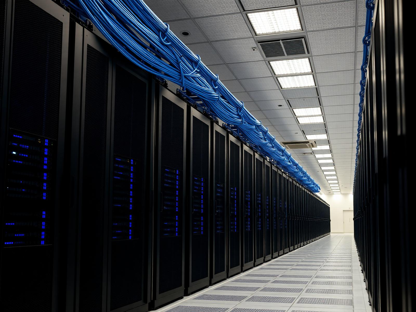 Enterprise server room aisle with shielded Cat6A trunk bundles routed on overhead ladder rack.