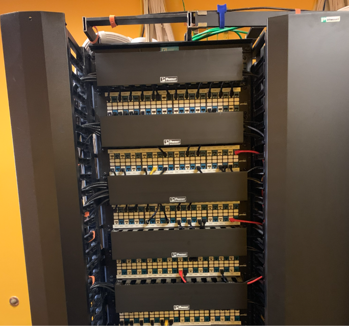 Full commercial network rack with organized Panduit patch panels, horizontal cable managers, and neatly dressed Cat6 patch cords.
