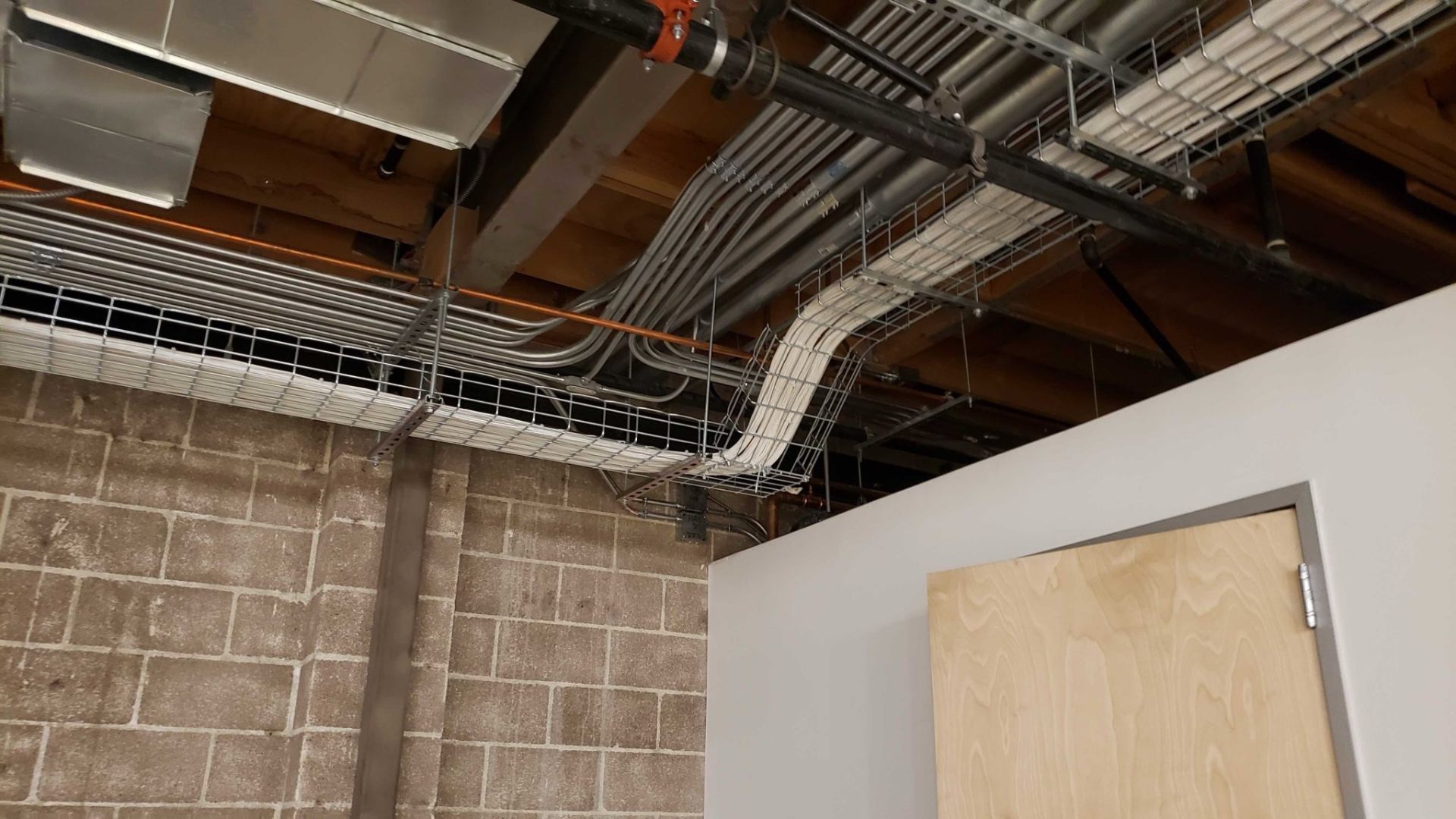 Overhead cable pathway and prefabricated tray routing above a commercial buildout in progress.