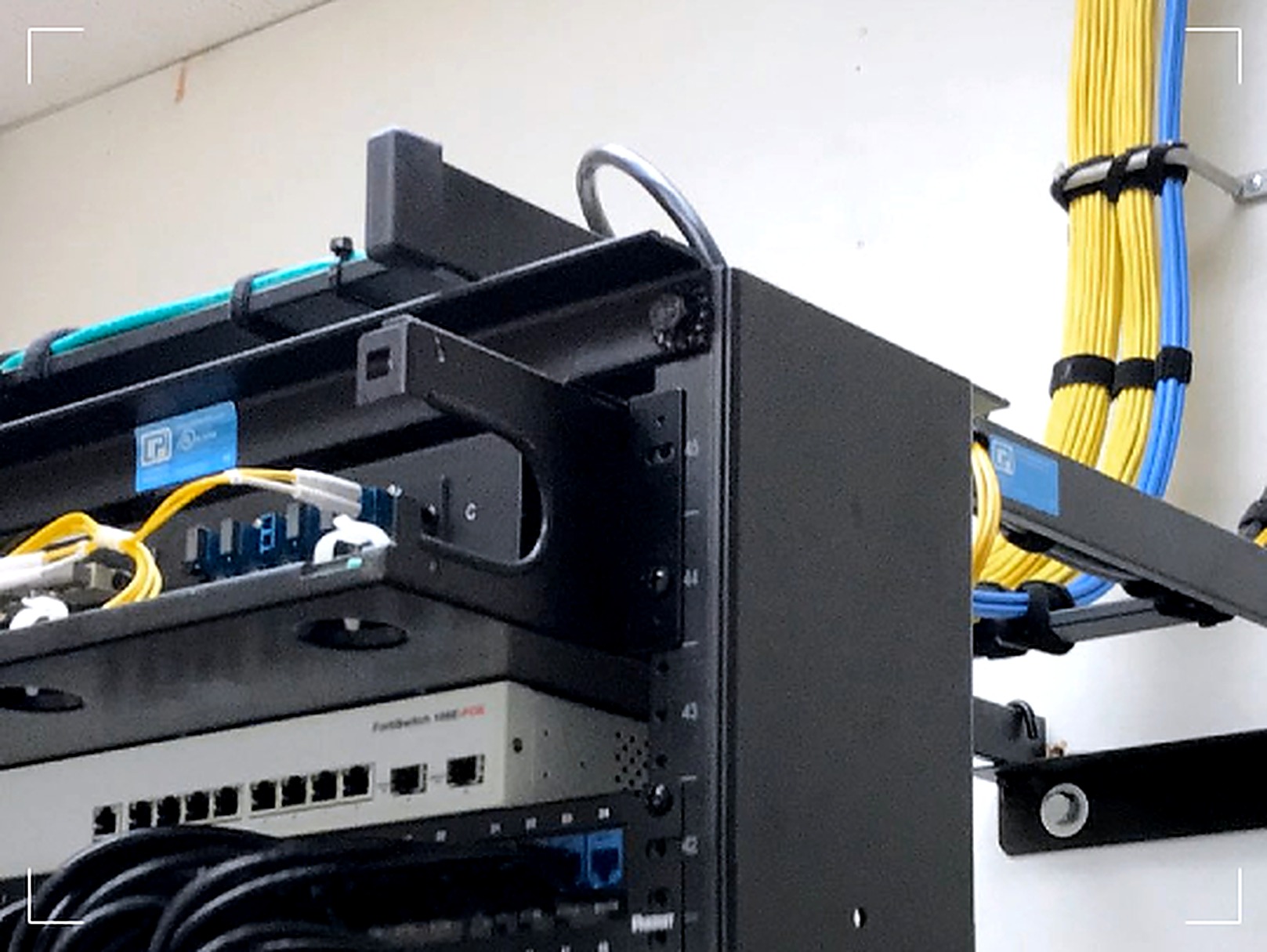 Wall-mounted fiber panel and top-of-rack switch in a data-center distribution enclosure.