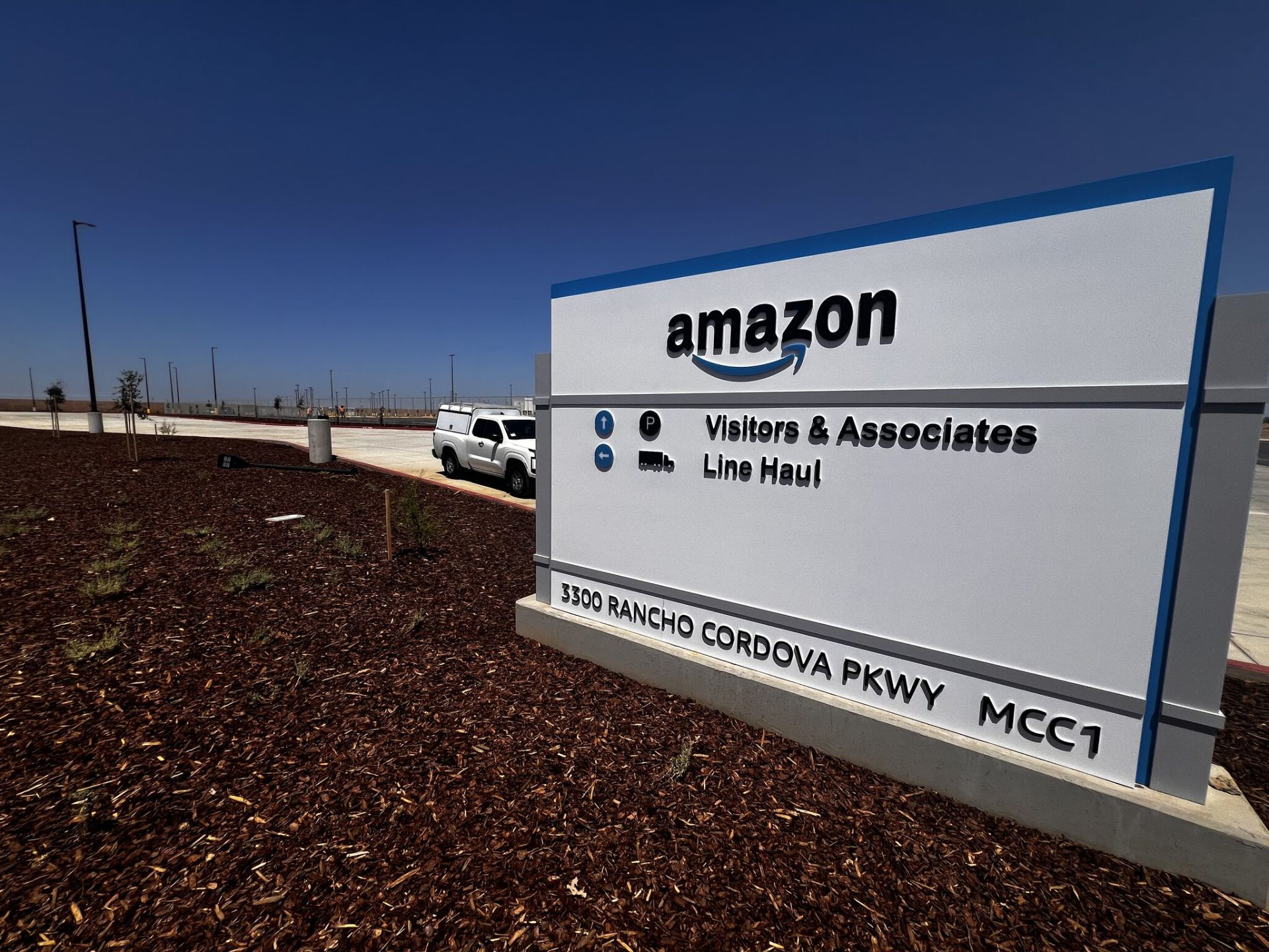 Exterior monument sign at the new Amazon MCC1 fulfillment facility at 3300 Rancho Cordova Parkway, with visitor and line-haul directional wayfinding — site where Access Cabling delivered the structured cabling and fiber backbone buildout.