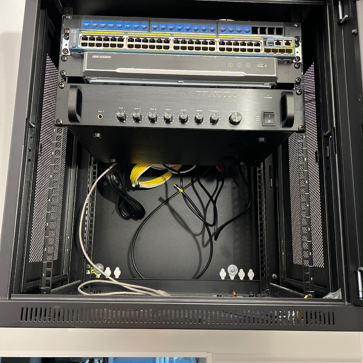 Restaurant IDF rack segmented into labeled CAMERAS, POS and DATA patch panels feeding dual Cisco Catalyst PoE+ switches with an OS2 single-mode fiber uplink handoff, installed and commissioned by Access Cabling.